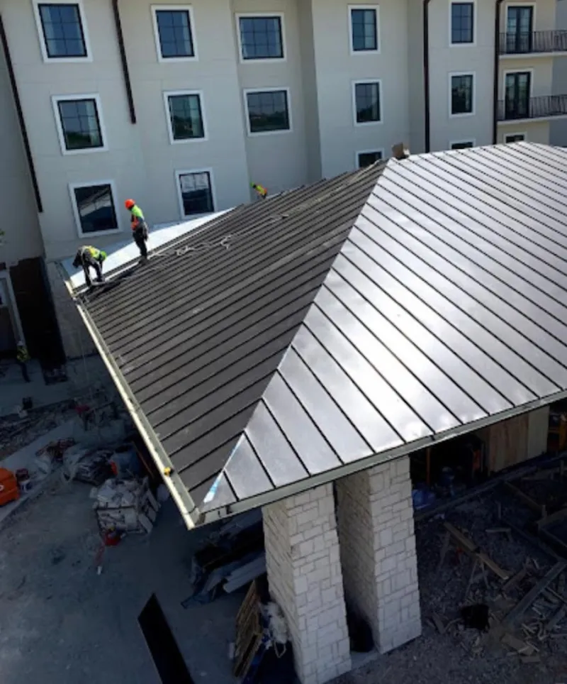 Crew installing standing seam metal roof panels on a commercial project in Westlake